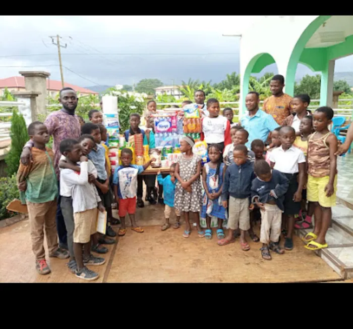A large group of children standing with ministry members in front of donated water, drinks and toiletries