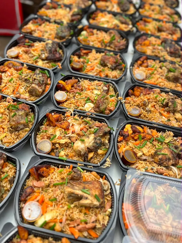 Rows of packed jollof rice meals with chicken and fried plantain