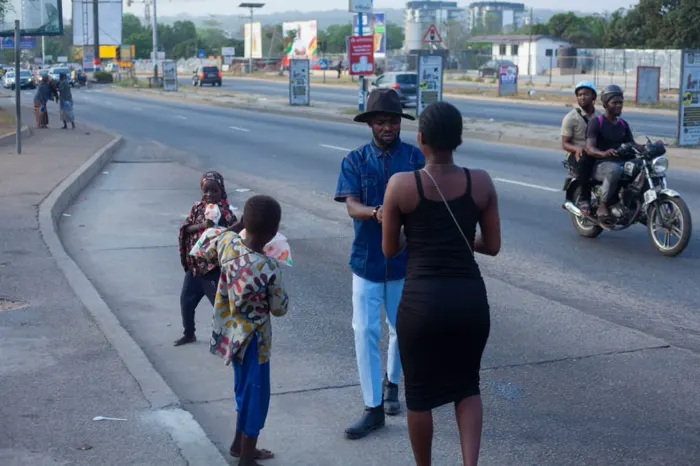 Two members greeting children holding food packs by the roadside