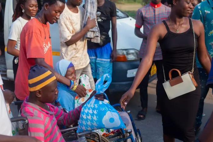 A member hands a food pack to a man seated in a wheelchair