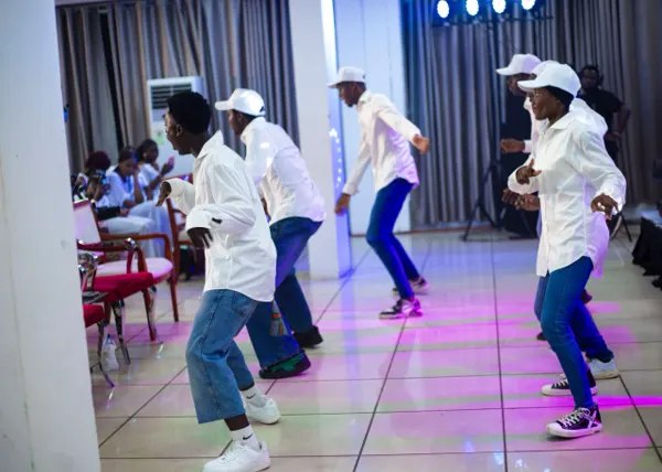 Dancers in white shirts, jeans and white caps performing a choreographed praise dance